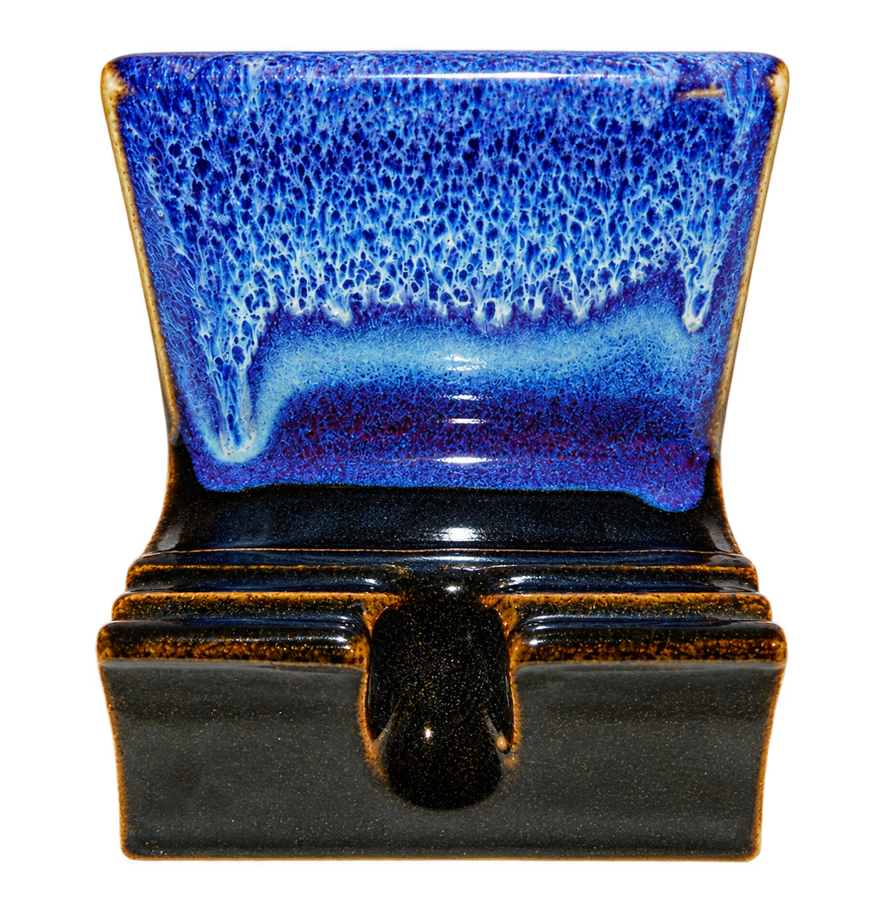 Handmade ceramic phone stand in deep cobalt blue and black glaze with a centered charging slot