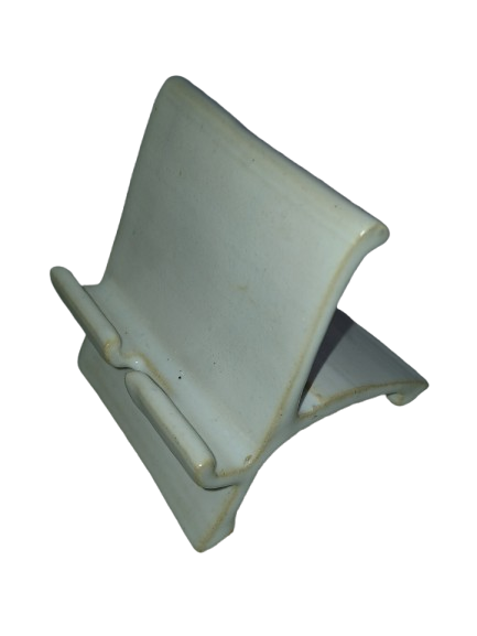 Handmade ivory ceramic lounger-style cell phone stand viewed at an angle
