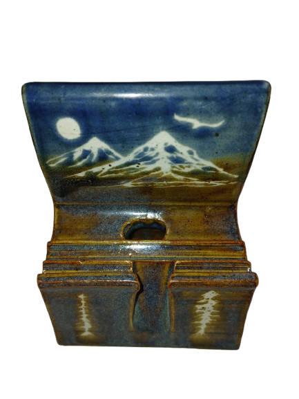 Handmade ceramic cell phone stand painted with snowy mountains, a moon, and a bird